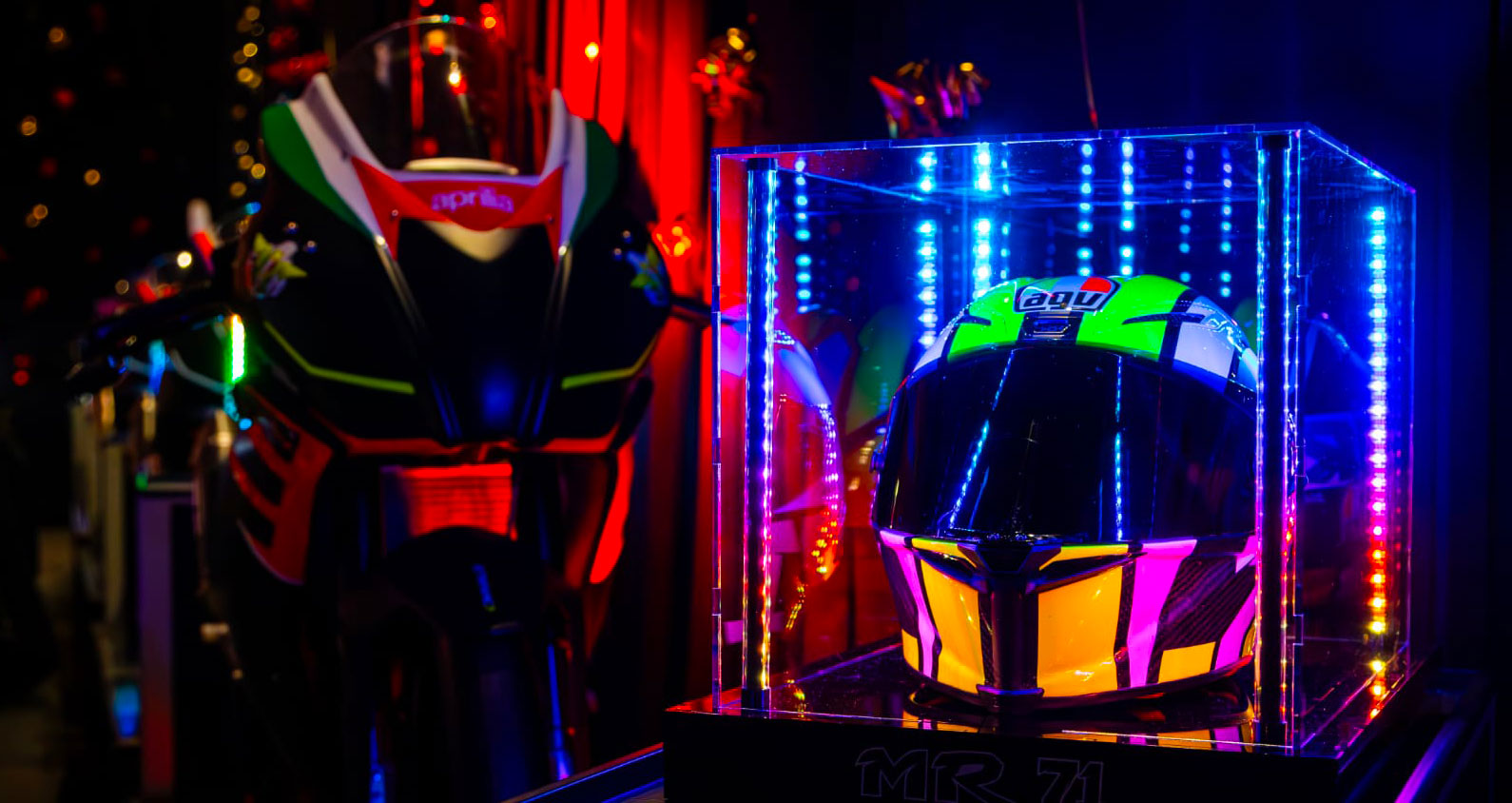 Un casco in una teca prodotta da Risalto, accanto ad una moto da corsa